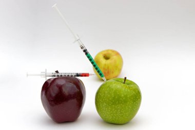 Kırmızı bir elmaya şırınga enjeksiyonu. Genetik modifiye edilmiş gıdalar. GDO enjeksiyonu.
