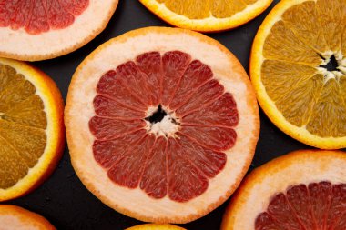 Dilimlenmiş turunçgiller ve siyah arka planda greyfurt meyveleri. Yakın plan.