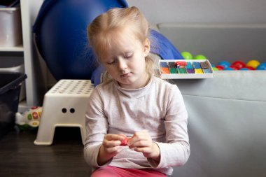 Küçük kız renkli modelleme kil, hamur ya da plastikle eğleniyor.