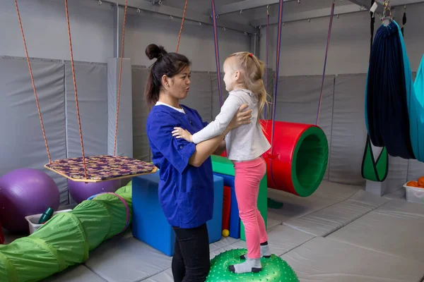 Fisioterapeuta trabajando con chica con pelota de gimnasio en centro de rehabilitación — Foto de Stock