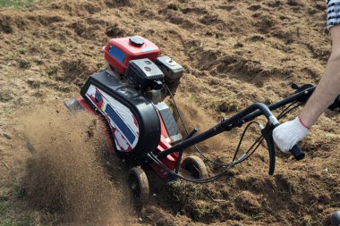 Çiftçi tarlayı ekiciyle sürüyor, sebze ekmeye hazırlıyor, güneşli bir günde.