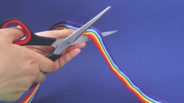 Erkek eli makaslı eşcinsel gururu kurdelesini kesiyor. LGBT toplumuna karşı saygısızlık ve ayrımcılık kavramı