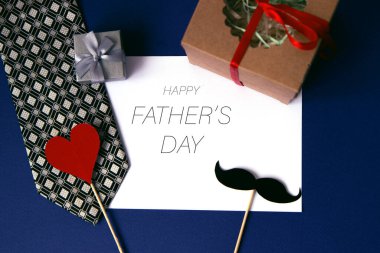 Beyaz kağıtta Mutlu Babalar Günü mesajı çerçeveli ve mavi arka planda hediyeler