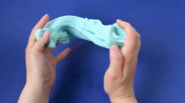 Çamurla oynamak, eğlence ve stres atmak için yapışkan maddeyi germek. Yaklaş ve üst görünümde kadın eli mavi parlak balçık tutuyor, sıkıyor..