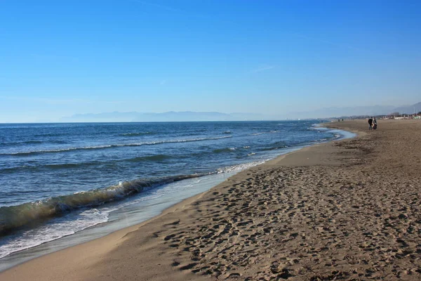 The Versilia beach, a sandy expanse of soft and warm colors in front of the Apuan Alps. The silence of winter, no one in the cold — Stock Photo, Image