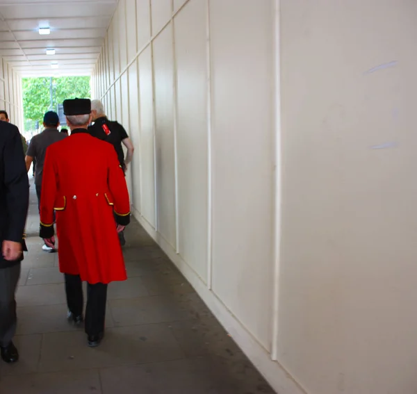 Figura inglesa con la espalda a la familia real de Londres, llevando un largo abrigo rojo . —  Fotos de Stock