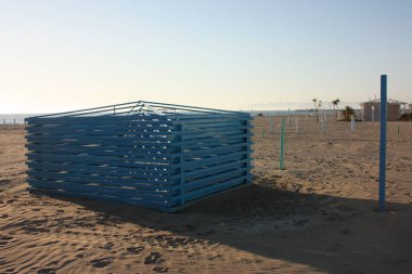 Kumsalda devam eden bir çalışma var. Açık alanda, borularla turuncu barlar arasında mevsimlik açık denizlerden önce