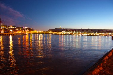 Hollanda 'nın başkenti Amsterdam' ın kanal suları üzerinde romantik bir sonbahar akşamı manzarası. Binaların ve gökdelenlerin ışıkları ve aydınlatmaları arasında.