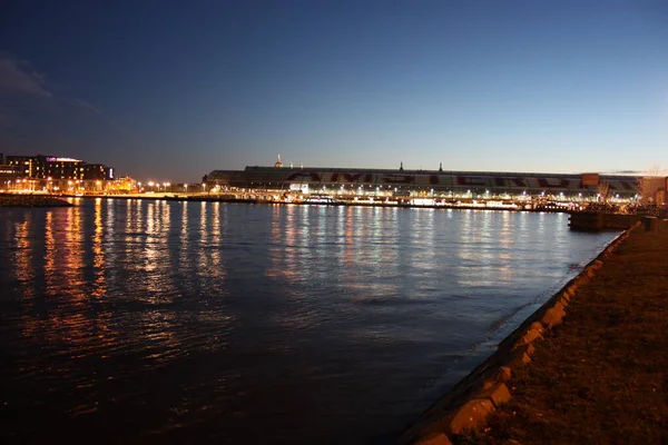 Panorama romantique du soir d'automne sur les eaux du canal de la ville métropolitaine néerlandaise d'Amsterdam, parmi les lumières et les illuminations des bâtiments et des gratte-ciel — Photo