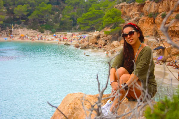 Yazlık kıyafetleriyle mutlu Avrupalı kız Eylül 'de İbiza' da tatilde. Cala Salada 'da, Balear Denizi' nin üzerindeki bir uçurumda oturuyor.