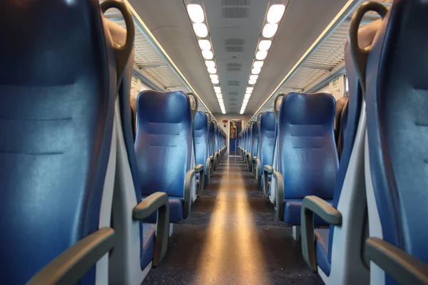 Asientos azules alineados a lo largo del pasillo de un tren regional sin pasajeros durante el día —  Fotos de Stock
