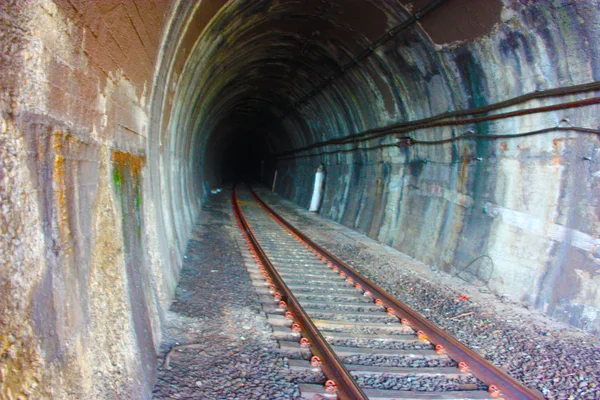 Tmavě černý stinný tunel v podzemním tunelu v jeskyni železnice podél kolejí vlaku k nádraží — Stock fotografie