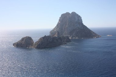 The magical island of Es Vedra with the small islet of Es Vedranell next to it in front of the coast of Cala d'Hort in the tourist island of Ibiza in the midst of nature between cliffs, beaches and co