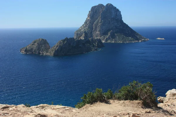 La mágica isla de Es Vedra con el pequeño islote de Es Vedranell junto a ella frente a la costa de Cala d 'Hort en la isla turística de Ibiza en medio de la naturaleza entre acantilados, playas y co — Foto de Stock
