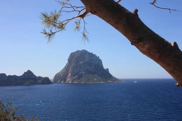 La isla de Es Vedra entre el cielo azul y el mar azul de jalá las costas ibicencas frente a la playa Cala D 'Hort en las Islas Baleares — Foto de Stock