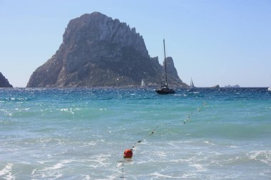 Es Vedra adası. Mavi gökyüzü ve mavi deniz arasında. Balear Adaları 'ndaki Cala D' Hort sahilinin önündeki İbizan kıyıları.