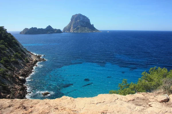La isla de Es Vedra entre el cielo azul y el mar azul de jalá las costas ibicencas frente a la playa Cala D 'Hort en las Islas Baleares — Foto de Stock