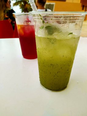 Yaz tatili için temiz plastik bir bardakta buzlu ve köpüklü naneli mojito.