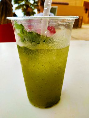 Yaz tatili için temiz plastik bir bardakta buzlu ve köpüklü naneli mojito.