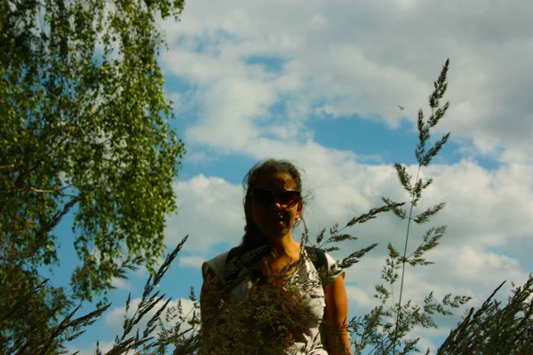 girl in contrast to the sky against the light between nature and the grass and the ears of wheat in summer in uk