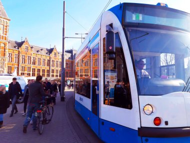 Hollanda 'da gündüz vakti Amsterdam tren istasyonunun önündeki Hollanda tramvayı.