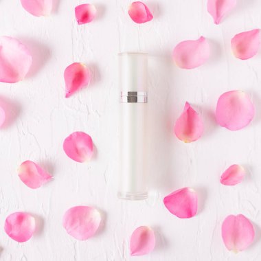 Beyaz arka planda pembe gül yaprakları olan doğal organik kozmetik şişe kaplarının üst görüntüsü.