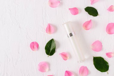 Beyaz arka planda pembe gül yaprakları olan doğal organik kozmetik şişe kaplarının üst görüntüsü.