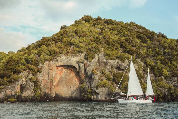 Taupo, North Island, Nieuw-Zeeland - 26 december 2016: Toeristen naderen de beroemde Mine Bay Maori Rock Carvings op Lake Taupo per cruiseboot — Stockfoto