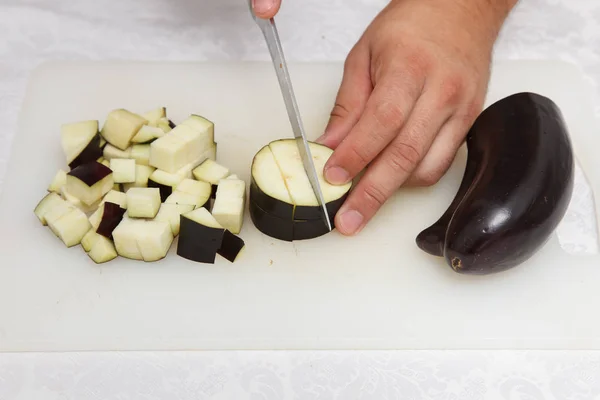 Подготовка пищи - разрезание баклажанов ножом на белом — стоковое фото