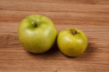 Ahşap masa üzerinde iki yeşil elma