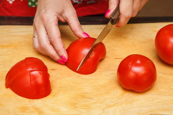 Измельчение помидоров ножом на деревянной доске — стоковое фото