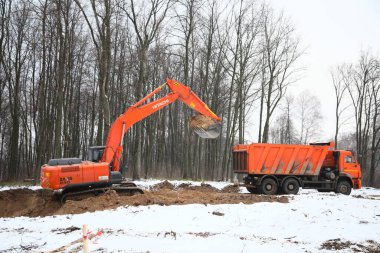 Kazan, Rusya - 12.12.2019. Kış boyunca inşaat alanında kazıcı ve çöp kamyonu.. 