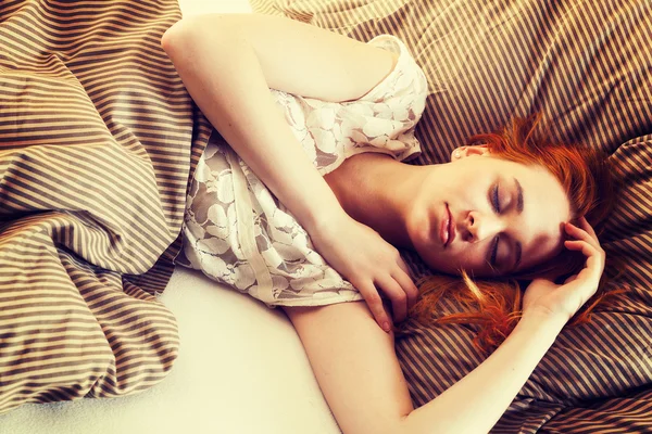 Mladá žena spí v posteli — Stock fotografie