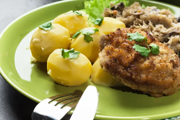 Fried pork schnitzel served with boiled potatoes and fried sauer — Stock Photo, Image