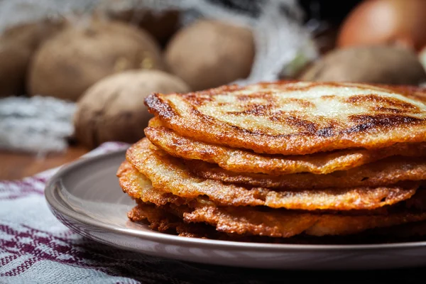 Kartoffelpuffer stapeln sich auf einem Holztisch. im Hintergrund po — Stockfoto