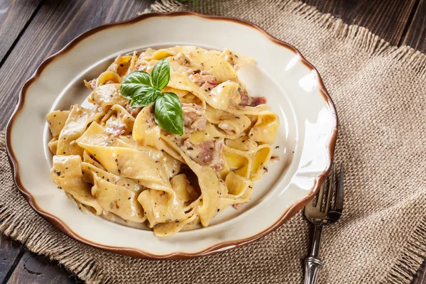 Pappardelle pasta med parmaskinka och ost på en tallrik — Stockfoto