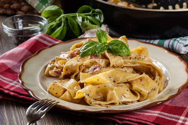 Pappardelle pasta med parmaskinka och ost på en tallrik — Stockfoto