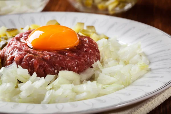 Steak tartare with egg yolk, onions and pickles — Stock Photo, Image