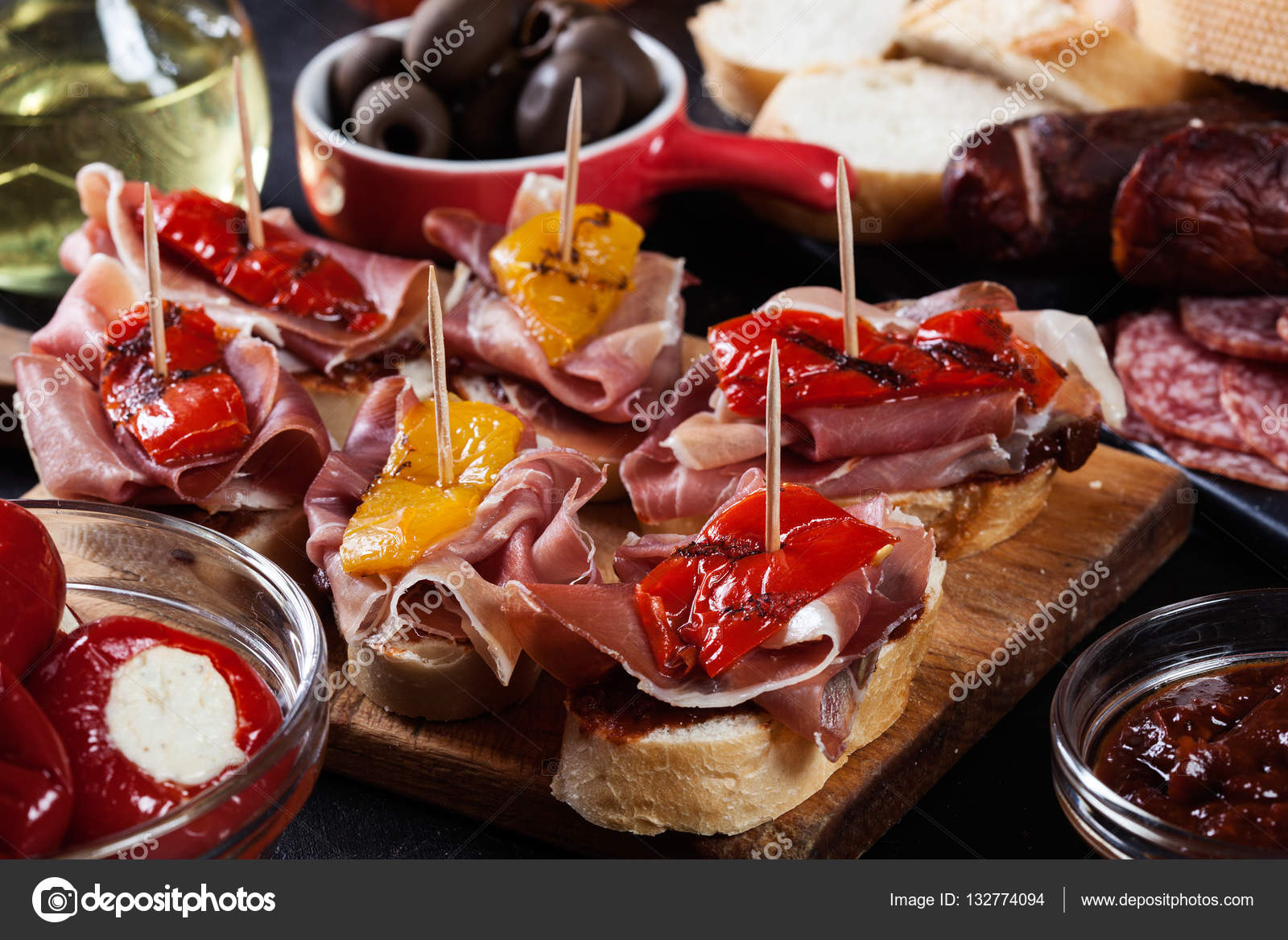 Spanish tapas with slices jamon serrano and grilled pepper. Also olives