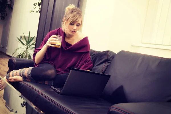 Jeune femme aux cheveux blonds travaillant sur son ordinateur portable à la maison — Photo