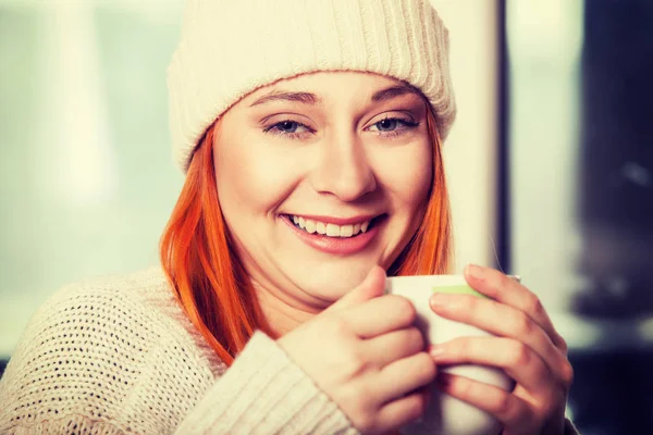 Frau trägt warme Kleidung und trinkt Heißgetränk — Stockfoto