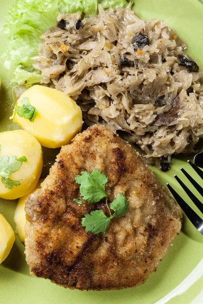 Fried pork schnitzel served with boiled potatoes and fried sauer — Stock Photo, Image