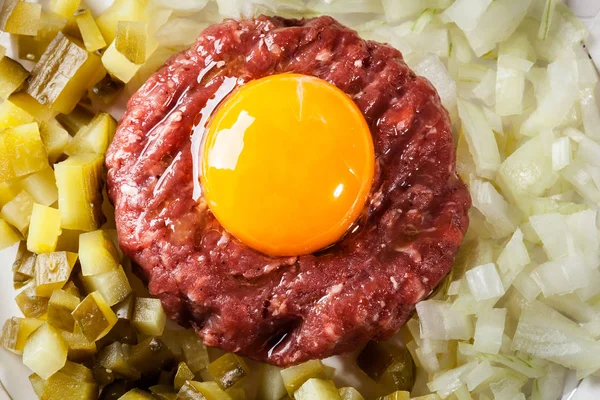 Steak tartare with egg yolk, onions and pickles — Stock Photo, Image