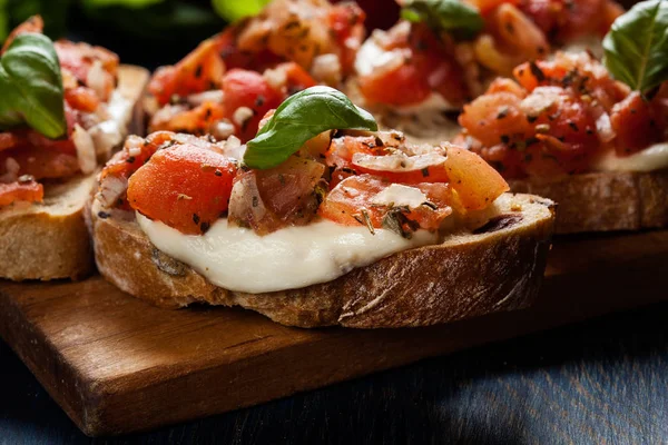 Bruschetta italiana com tomate torrado, queijo mussarela e — Fotografia de Stock