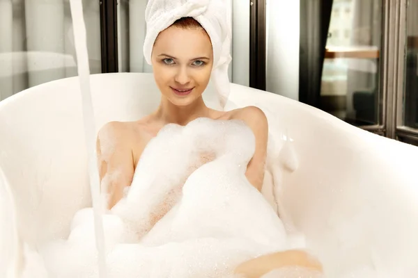 Jeune belle femme aux cheveux roux prend un bain moussant — Photo