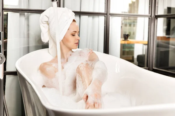 Jeune belle femme aux cheveux roux prend un bain moussant — Photo