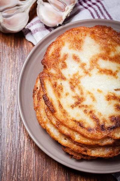 Stack of potato pancakes on a wooden table. In the background po — Stock Photo, Image
