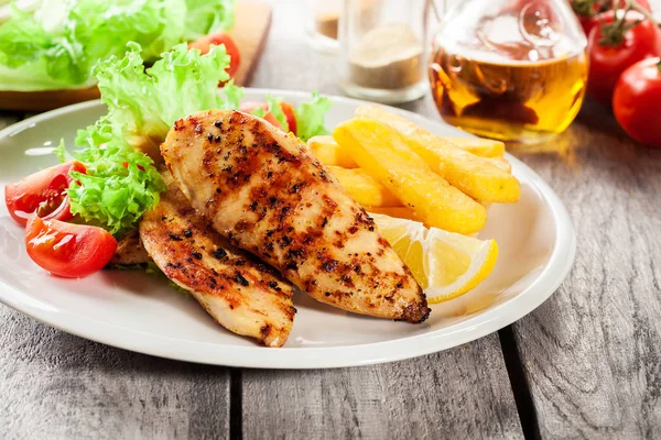 Seios de frango grelhados servidos com batatas fritas e salada fresca — Fotografia de Stock