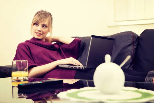 Молода жінка з світлим волоссям працює на ноутбуці вдома — стокове фото