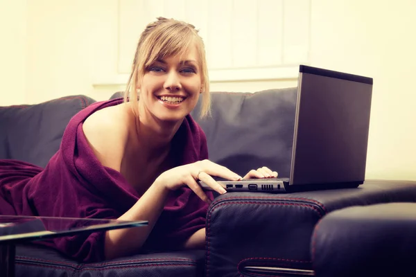 Ung kvinna med blont hår arbetar på hennes laptop hemma — Stockfoto